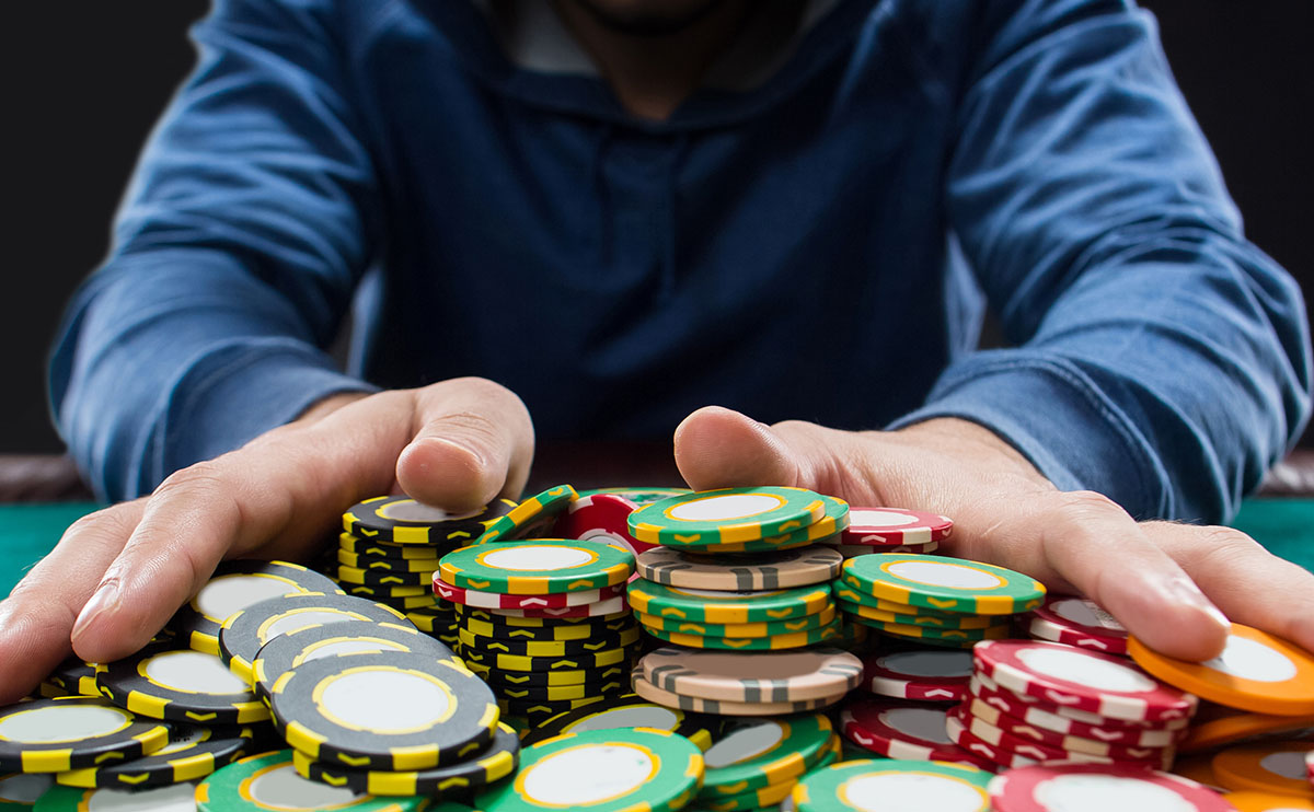 Jugador arrastrando una gran cantidad de fichas al centro de una mesa de póker